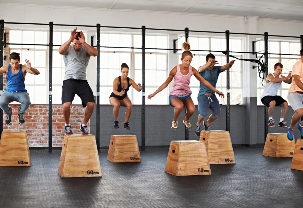 A fitness trainer leads a group class in a spacious, well-lit gym, demonstrating exercises and providing guidance to clients of various fitness levels